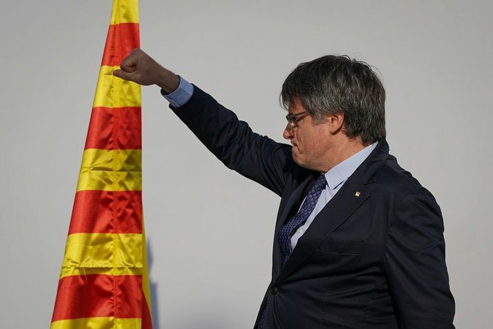 Carles Puigdemont með hnefa á lofti eftir að hann ávarpaði stuðningsmenn sína í Barcelona í dag. Í baksýn er katalónsi fáninn, La senyera.