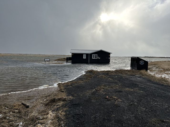 Hús við Nátthaga sem er umlukið sjó sem flætt hefur upp á land.