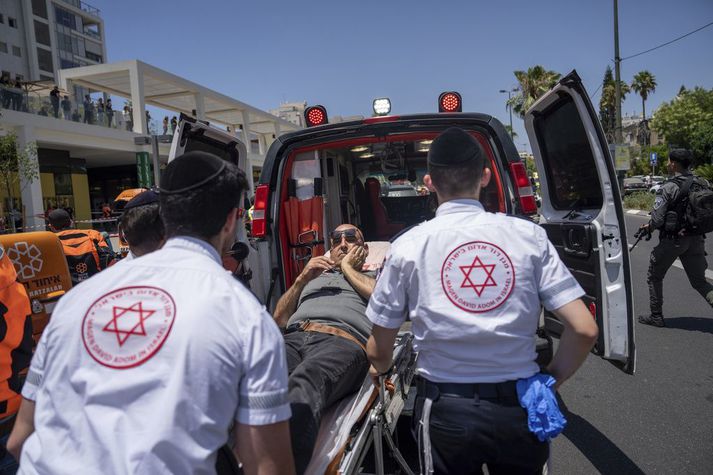 Ísraelskir sjúkraflutningamenn flytja mann af vettvangi árásar ungs Palestínumanns í Tel Aviv í dag.