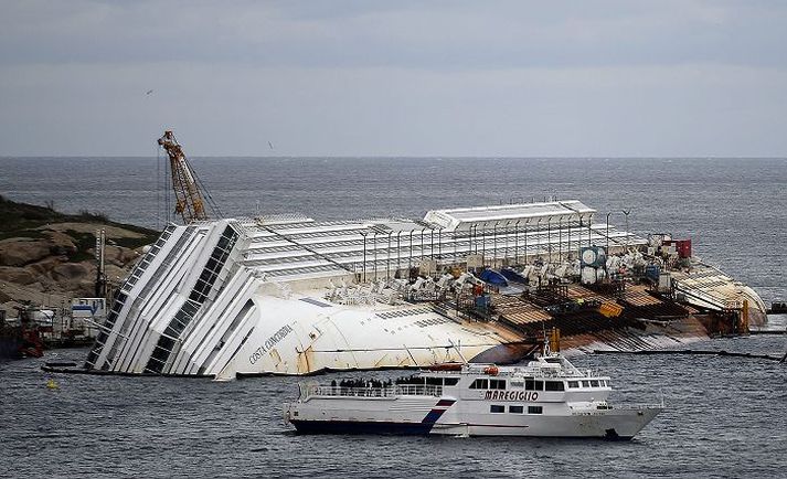 enn á strandstað Costa Concordia liggur enn við eyjuna, tæpu einu og hálfu ári eftir skipskaðann. Aðstandendur fóru að skipinu og minntust látinna þegar ár var liðið frá slysinu í janúar síðastliðnum. nordicphotos/afp