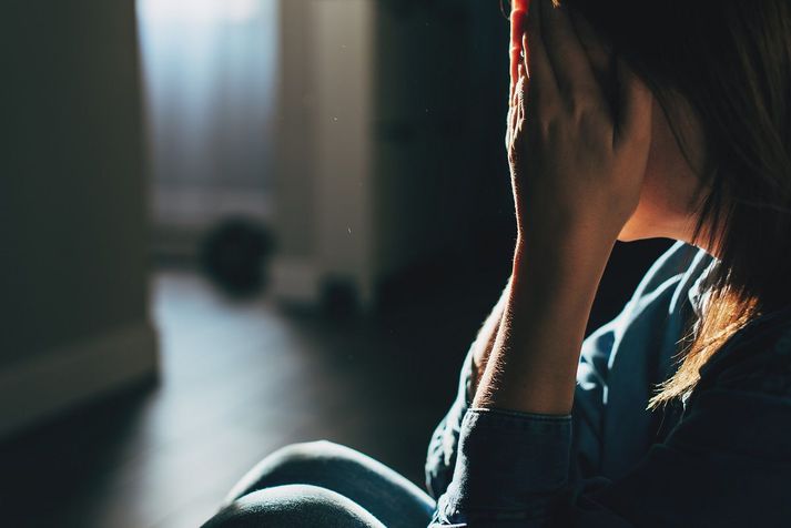 Silhouette of sad and depressed woman sitting on the floor at home