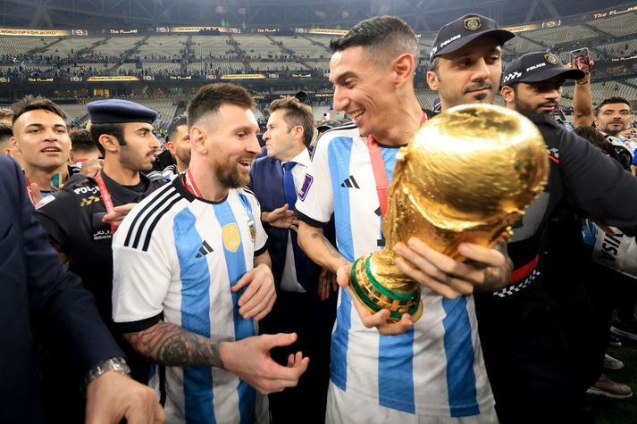 Ángel Di María með heimsbikarinn í höndunum og Lionel Messi sér við hlið eftir að Argentínumenn urðu heimsmeistarar í Katar 2022.