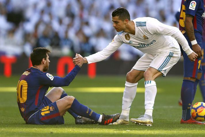 Cristiano Ronaldo hjálpar Lionel Messi á fætur þegar þeir mættust með Real Madrid og Barcelona í desember 2017.