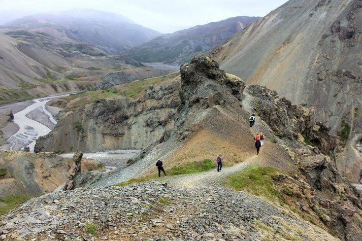 Göngufólk leggur af stað niður Illakamb. Skála- og tjaldstæði má sjá við Kollumúla.