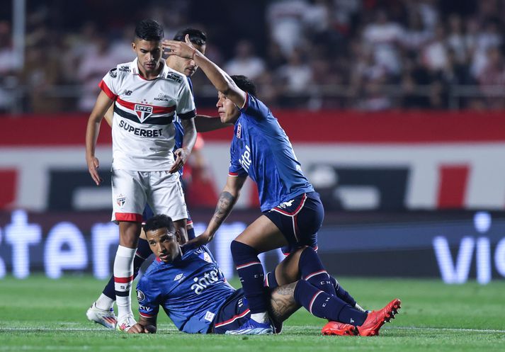 Liðsfélagi Juan Izquierdo kallar eftir hjálp eftir að Izquierdo hneig liður í leik Sao Paulo og Nacional í Copa Libertadores.