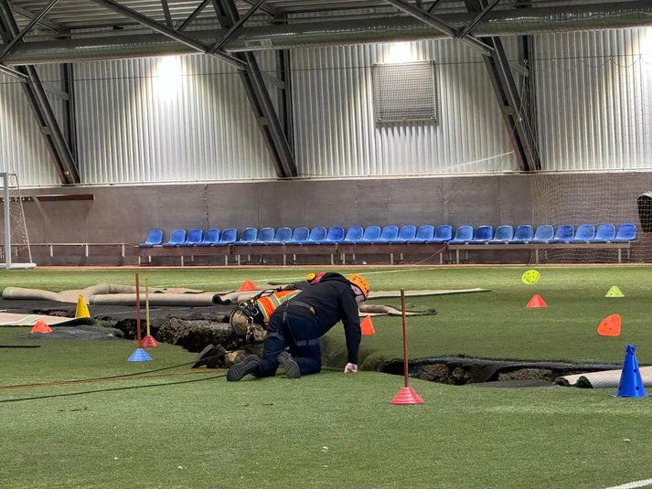 Fannar Jónasson bæjarstjóri í Grindavík horfir átta metra niður í jörðina af brún sprungunnar sem liggur í gegnum Hópið.