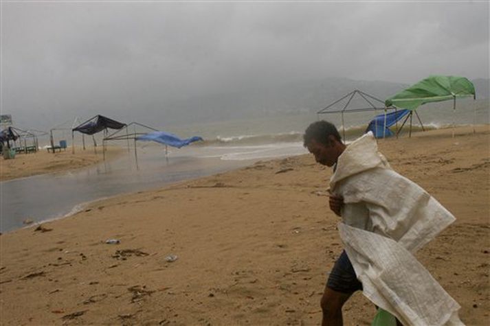 Fiskimaður gengur á ströndinni í Acapulco í Mexíkó þar sem hvassviðri og rigning, sem fylgt hefur fellibylnum Jóni, gekk yfir. Acapulco er vinsæll ferðamannastaður.