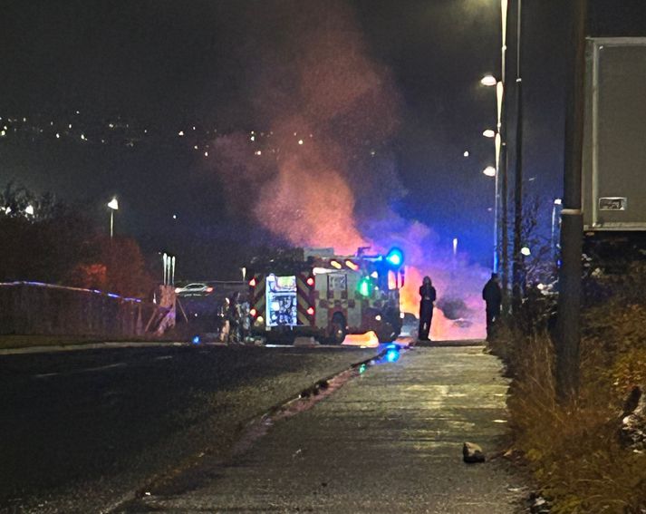 Bifreiðin stóð í ljósum logum þegar að slökkvilið bar að garði.