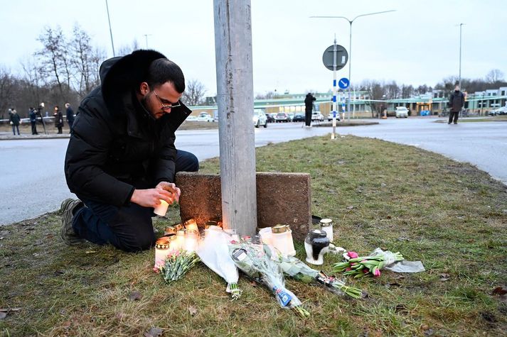 Maður kveikir á kerti við Risbergska-skólann í Örebro.