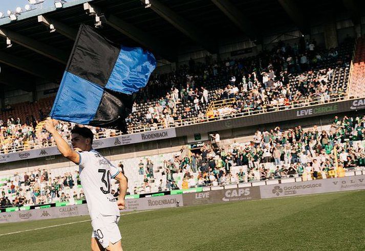 Ardon Jashari, leikmaður Club Brugge, hleypur um með fána félagsins inn á vellinum.