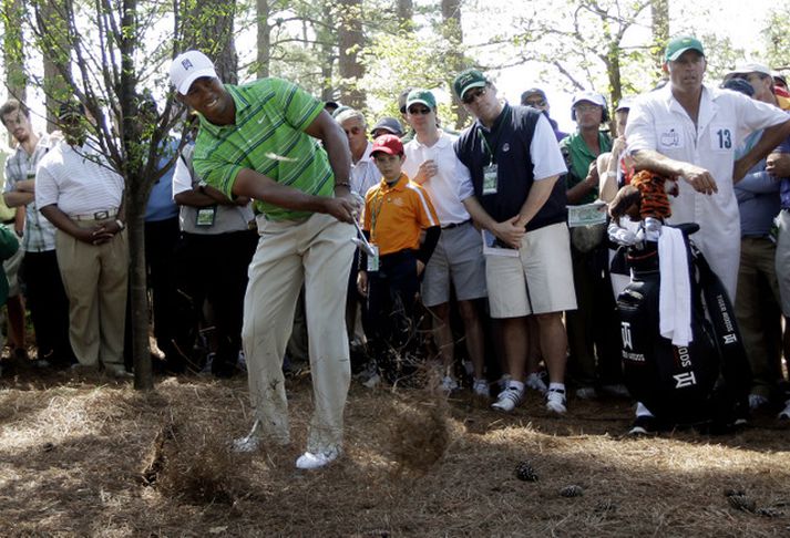 Tiger Woods getur líka lent utan brautar og hér klórar hann sig út úr vandræðum á Augusta vellinum í gær.