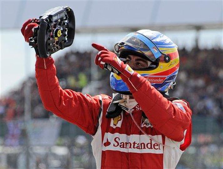 Fernando Alonso bendir á stýrið með Ferrari merkinu eftir sigurinn á Silverstone í gær.