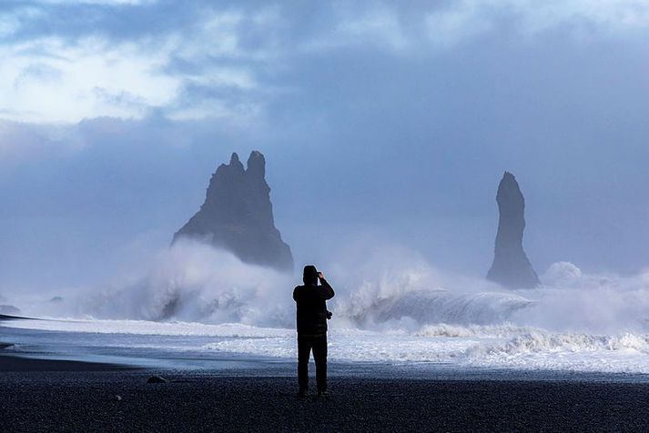 Ferðamaður fylgist með öldunum í Reynisfjöru.