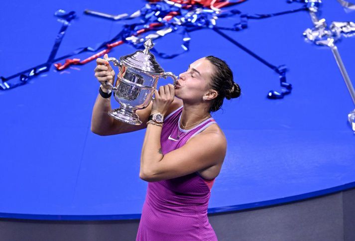 Aryna Sabalenka smellir kossi á verðlaunagripinn, í New York á laugardaginn.