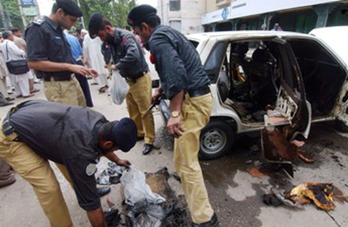 Pakistanska lögreglan í borginni Peshawar slekkur eld í bíl sem hlaðinn var sprengiefnum.