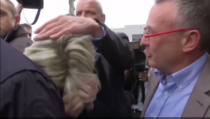 Lífvörður grípur um höfuð Marine Le Pen til að verja hana frá frekara eggjakasti.