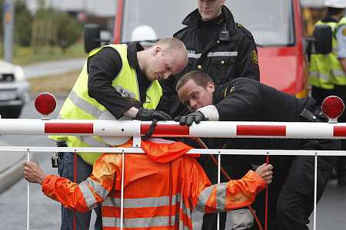 Unnið að því að losa mótmælanda sem hafði hlekkjað sig við aðalhlið álversins