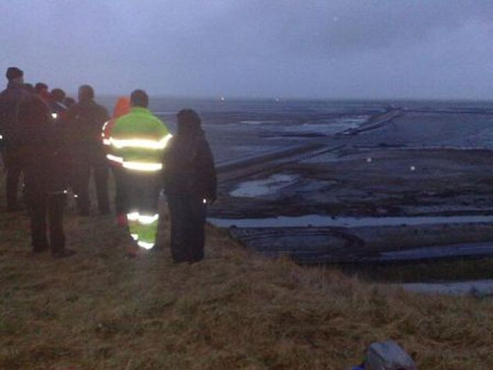 Fólk fylgist með flóðinu sem hækkar hægt og rólega.