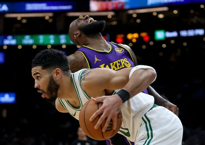 Jayson Tatum brunar framhjá LeBron James sem fékk högg á kinnina.