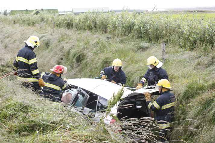 Hér sést slökkviliðið að störfum við það að klippa þak bílsins af svo hægt sé að bjarga ökumanninum.