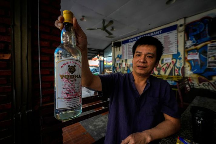 Stjórnandi gistiheimilis í Vang Vieng í Laos heldur á vodkaflösku á bar þess. Áströlsku stúlkurnar sem veiktust dvöldu þar.