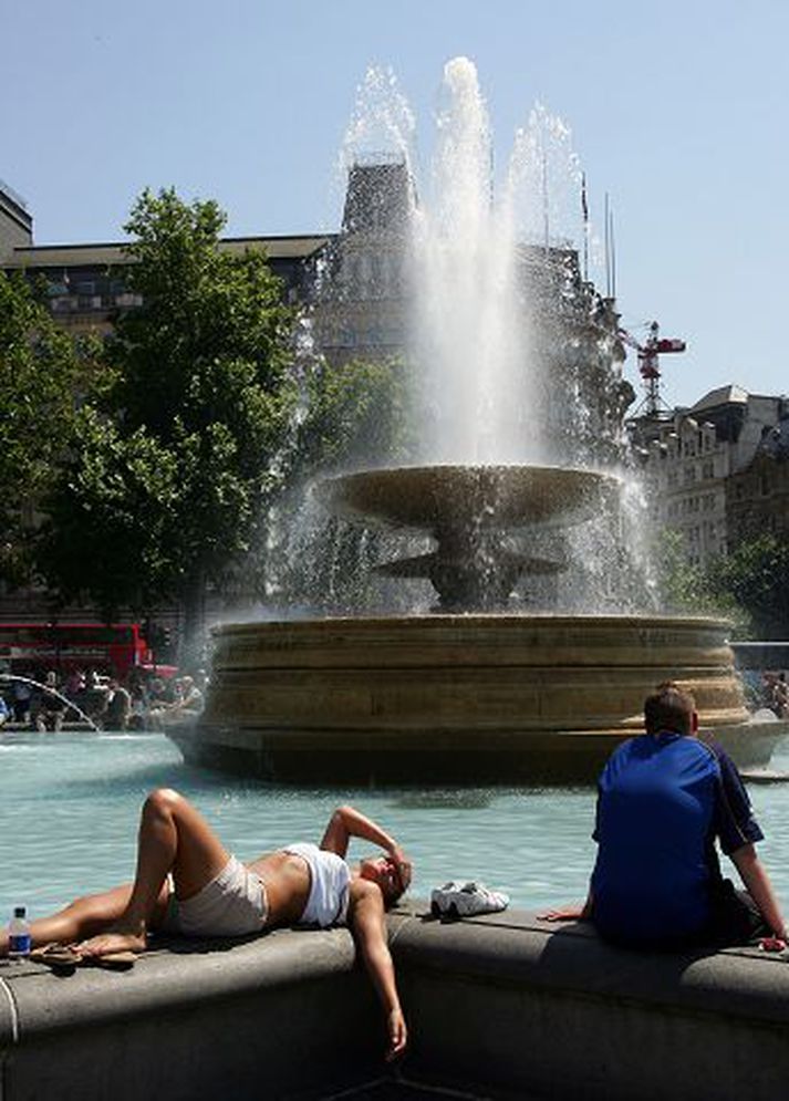 Í sólbaði	Þessi stúlka virtist ekki þjást mikið í hitanum á Trafalgartorgi í London í gær, að minnsta kosti ekki á meðan hún gat legið kyrr við gosbrunninn.