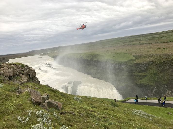 Þyrla var kölluð út eftir að ferðamaður rann á steinhellu við myndatöku við fossinn síðdegis í gær.