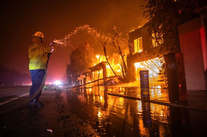 Slökkviliðsmaður í Los Angeles reynir hér að sprauta vatni á eldanna í Palisades en má sín lítils.