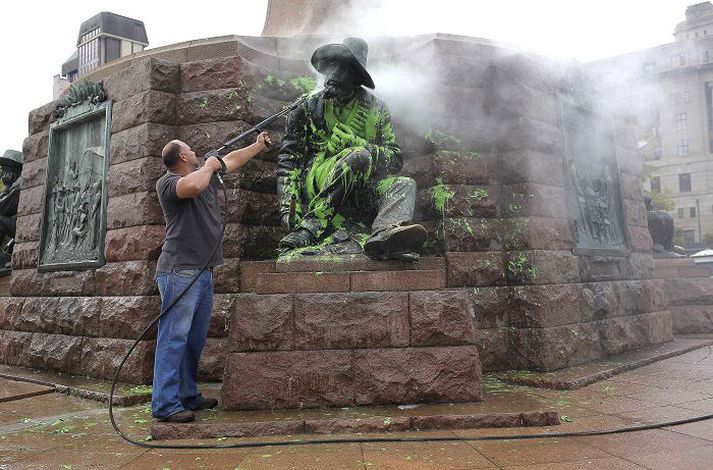 Bæjarstarfsmaður í Pretoríu þvær græna málningu af minnismerki um Paul Kruger.