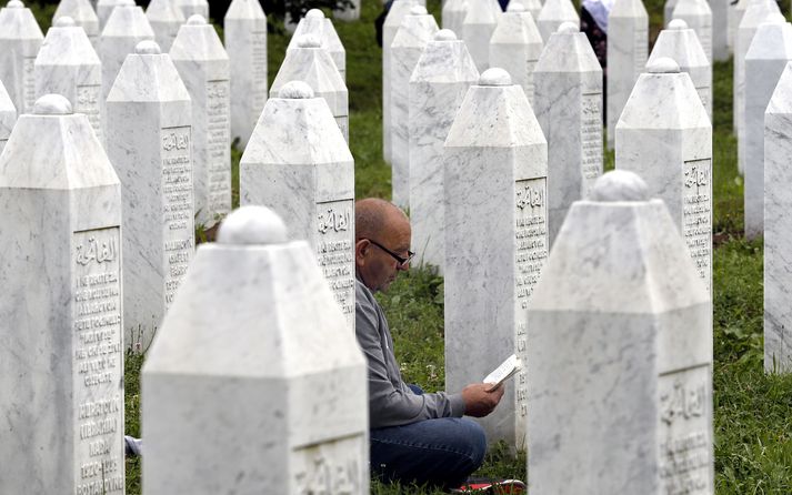 Maður á bæn við minnisvarða um fórnarlömb fjöldamorðsins í Srebrenica.