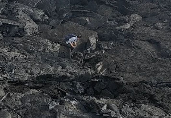 Fótur ferðamannsins fer í gegnum þunna skorpuna á nýstorknuðu hrauninu.