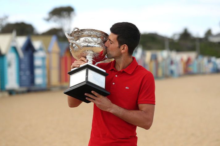 Novak Djokovic smellir kossi á verðlaunagripinn á ströndinni í Melbourne.