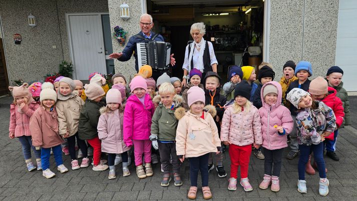 Sigurður og Rúna með leikskólabörnunum, sem heimsóttu þau og sungu hressilega við undirleik Sigurðar á harmonikkuna.