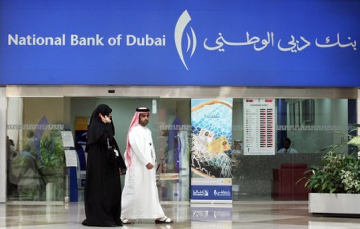 Maður gengur framhjá National Bank of Dubaí.