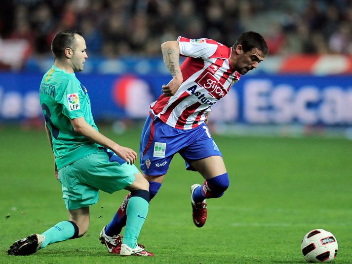 Andres Iniesta hjá Barcelona í baráttu við Nacho Novo, leikmann Sporting de Gijon.