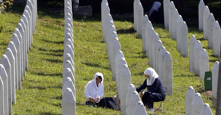 Konur kveikja á kertum í kirkjugarðinum fyrir alla þá sem létust í þjóðarmorðunum árið 1995 í Srebrenica. 