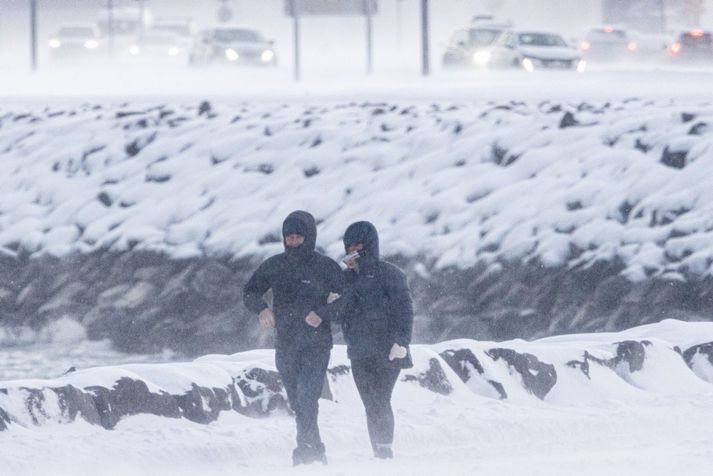 Fólk á göngu í snjóstormi og kulda. Sennilega verður veðrið einhvern veginn svona á morgun.